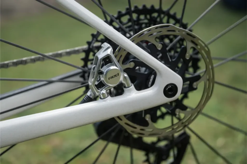 Primer plano de la pinza de freno de disco trasero y el cassette de una BMC Kaius 01, mostrando la ingeniería de precisión de una bicicleta rápida.