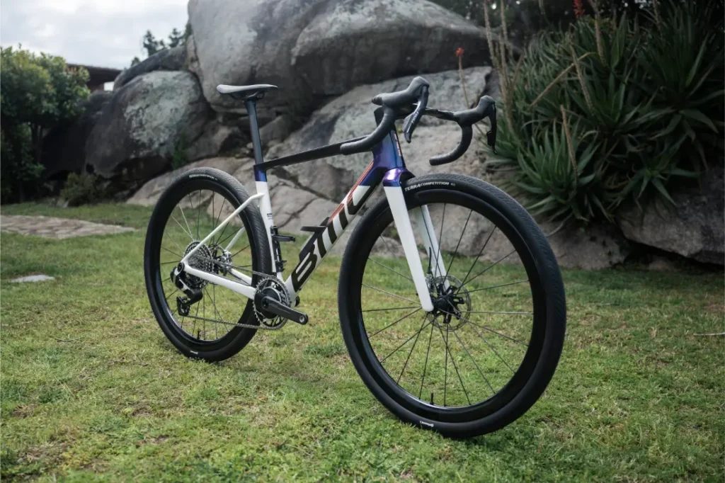 A BMC Kaius 01, una bicicleta actual con manillares de carrera y frenos de disco, está aparcada sobre el césped cerca de grandes rocas y plantas.