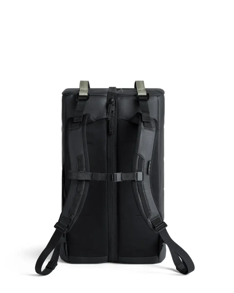 Una mochila Db negra mostrada desde atrás, con correas acolchadas para los hombros, una correa para el pecho y una cremallera central, perfecta para cualquier sistema de viaje.