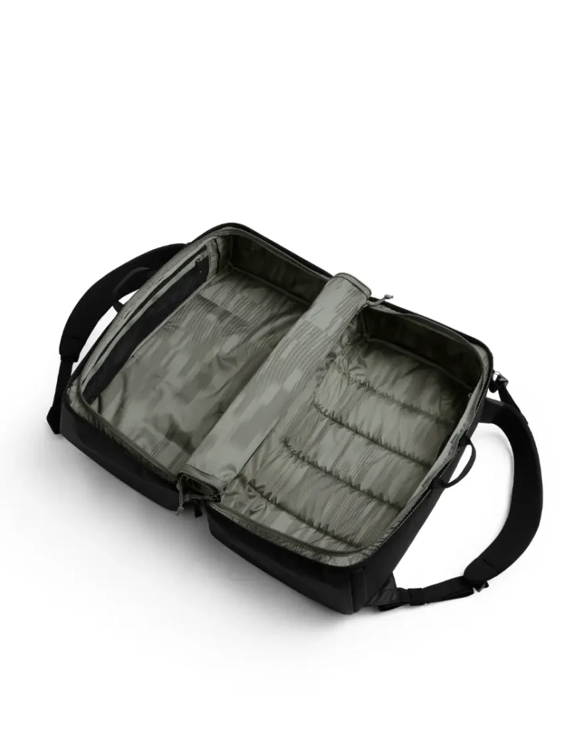 Mochila de viaje negra abierta de ASSOS sobre fondo blanco, que muestra sus compartimentos interiores vacíos y sus correas organizadoras, perfecta para el sistema de viaje de los ciclistas que buscan un almacenamiento eficiente.