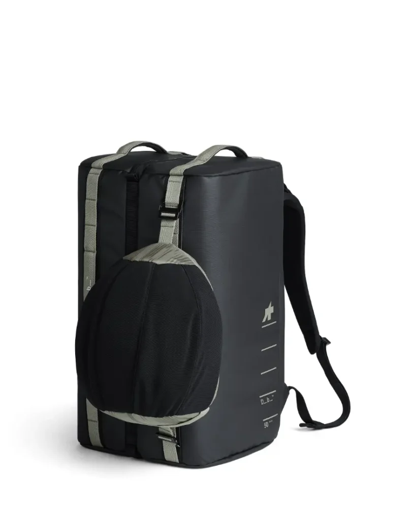Una mochila rectangular negra con correas grises, que se muestra de pie, cuenta con un bolsillo lateral ventilado que contiene una pelota negra y gris, perfecta para ciclistas y diseñada en colaboración con ASSOS x Db para tu sistema de viaje.