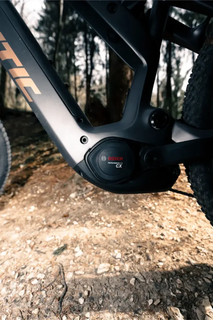 Primer plano del sistema de motor Bosch CX Gen5 de una Fantic Sierra e-MTB, mostrando parcialmente el cuadro y el neumático delantero en un sendero de tierra.