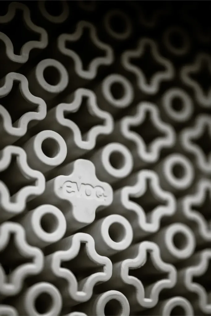 Detalle de las piezas de espuma entrelazadas en forma de cruz del EVOC Torso Protector en talla XS. Una pieza central muestra "EVOC", destacando el patrón uniforme y el enfoque en la seguridad de este material protector.