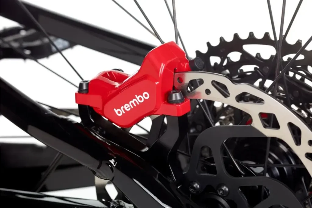 Primer plano de una pinza de freno de disco hidráulico Brembo GR-PRO roja montada en una e-MTB, mostrando el rotor de freno y parte del cuadro de la bicicleta: frenos ideales para los entusiastas de la gravedad.