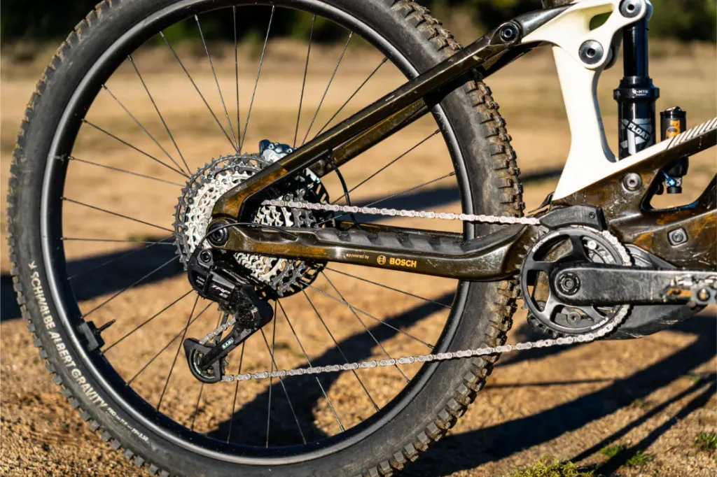 Primer plano de la rueda trasera y la transmisión de una bicicleta eléctrica de montaña, destacando los engranajes, la cadena, el desviador y el potente sistema de motor Bosch Performance Line CX.
