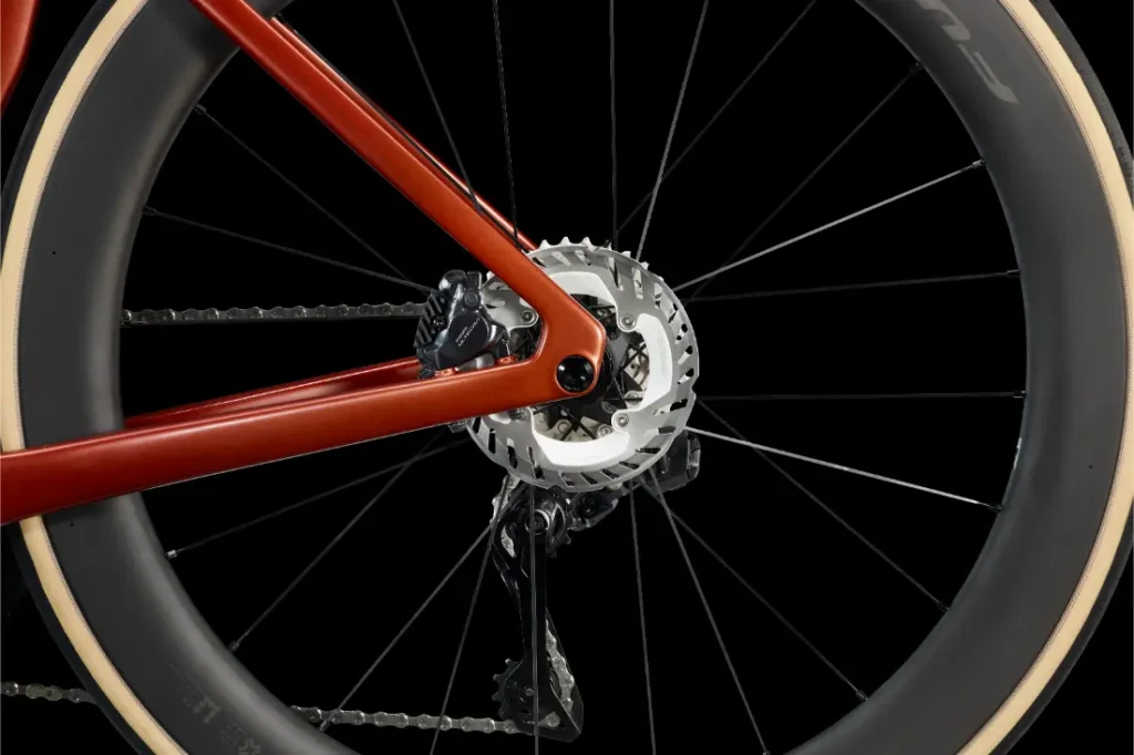 Primer plano de la rueda trasera de una LOOK 795 Blade RS 3, en el que se aprecian el freno de disco, el desviador, la cadena y parte del cuadro rojo sobre un fondo negro.