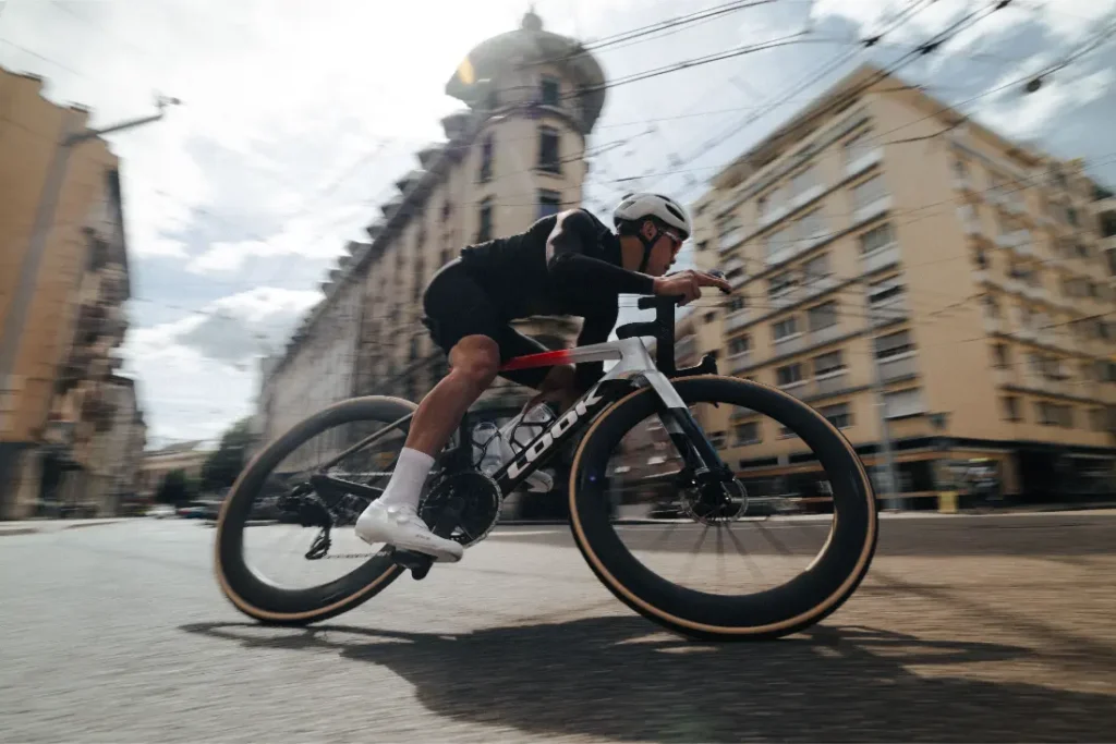 Un ciclista con casco recorre a gran velocidad una calle de la ciudad de Nevers, flanqueada por edificios altos, montado en una LOOK 795 Blade RS.
