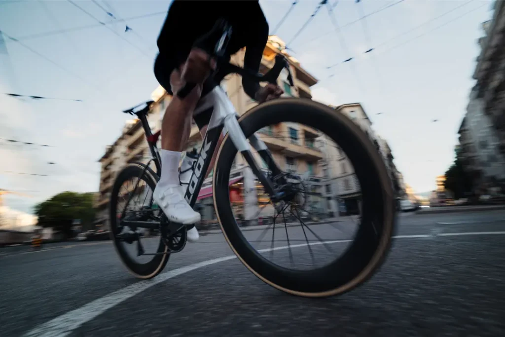 Un ciclista con zapatillas blancas circula en una bicicleta de carretera LOOK 795 Blade RS 3 por una calle de Nevers, con edificios y cables aéreos visibles al fondo.