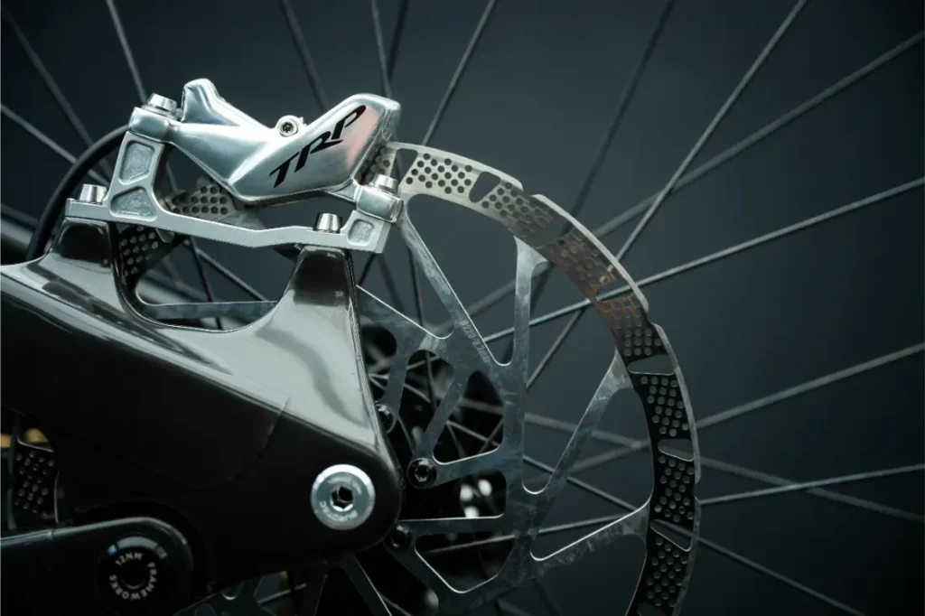 Primer plano de un sistema de frenos de disco para bicicleta que incluye una pinza TRP EVO PRO y un disco ventilado, edición limitada, sobre un fondo oscuro.