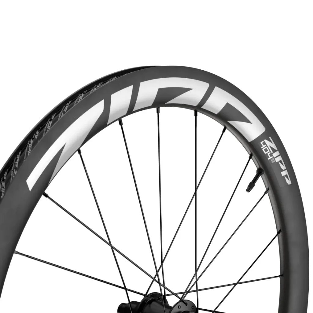 Primer plano de una rueda de bicicleta de carbono Zipp 404 S en el que se aprecian los radios y el llamativo logotipo «ZIPP» en blanco en la llanta, lo que destaca su velocidad y su diseño de alta gama. Ideal para quienes buscan rendimiento a un precio competitivo.