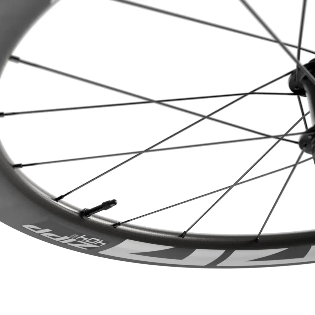 Primer plano de una rueda de bicicleta de carbono Zipp 404 S en el que se aprecian los radios, la válvula y el logotipo de la llanta sobre un fondo blanco, diseñada para ofrecer la máxima velocidad y rendimiento. Descubre más sobre su competitivo precio.