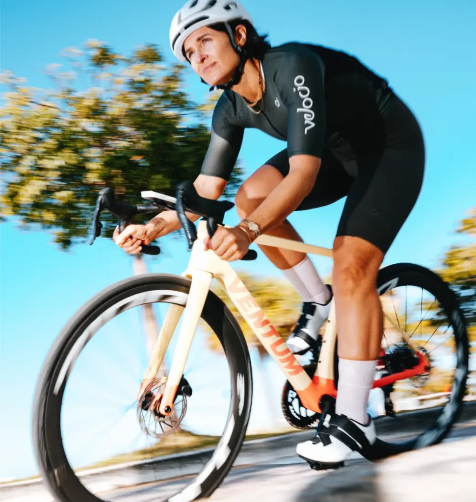 Una persona que lleva casco y equipación de ciclismo monta en una bicicleta de carretera con ruedas Zipp 404 S al aire libre en un día soleado; la velocidad es evidente al ver cómo los árboles y el cielo pasan borrosos por el fondo.