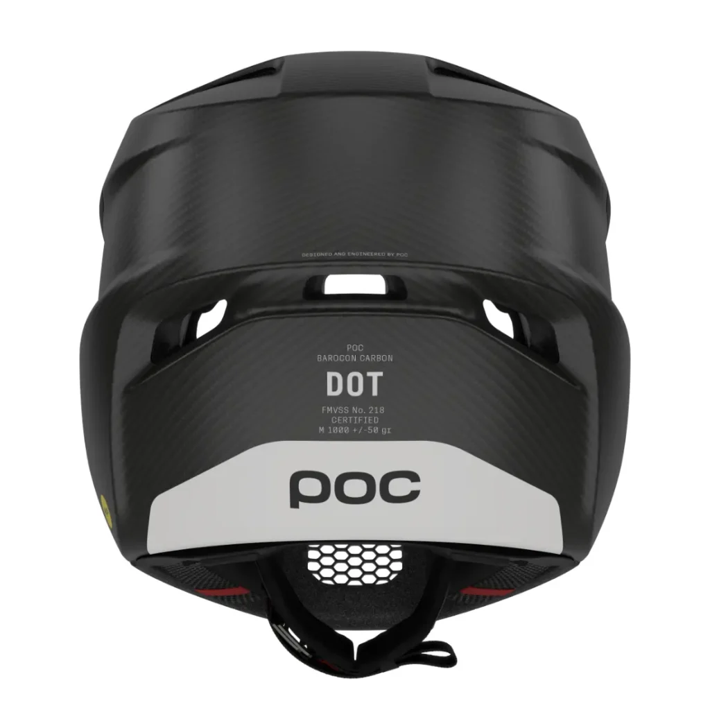 Casco integral POC Barocon Carbon negro, visto desde atrás, en el que se aprecia una etiqueta blanca con los datos de certificación y el logotipo de POC. La superficie presenta una textura de fibra de carbono, ideal para los ciclistas de descenso.