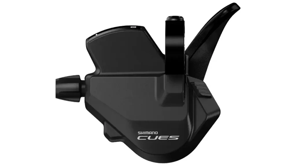 Maneta de cambio de marchas Shimano CUES de color negro, con las palancas y el logotipo visibles, representada sobre un fondo blanco.