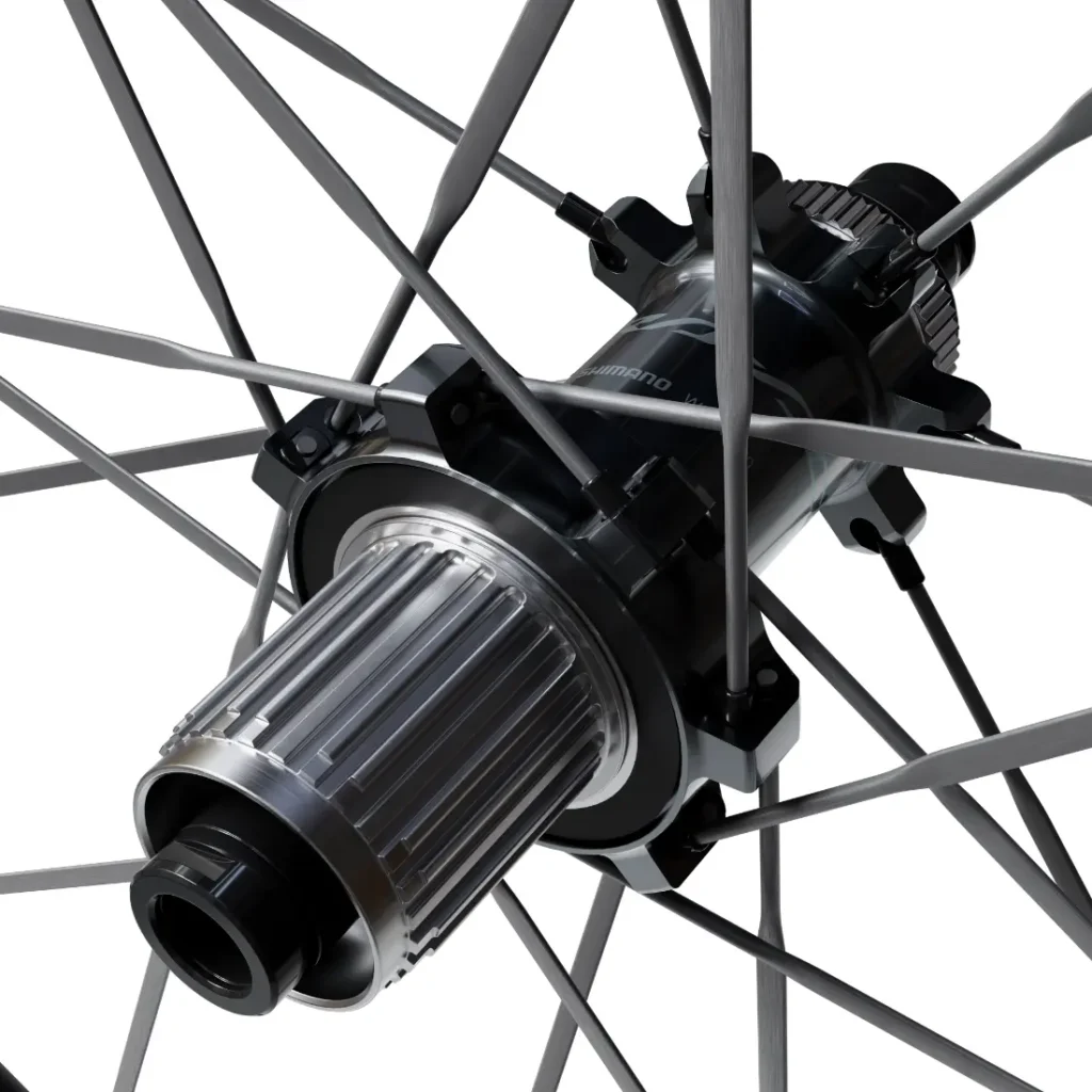 Primer plano del buje de una rueda de bicicleta con radios metálicos, en el que se aprecian con detalle los componentes y las piezas mecánicas de la serie Shimano Dura-Ace WH-R9370. La imagen destaca la ingeniería de precisión y el diseño avanzado característicos de las ruedas de carbono para el ciclismo de alto rendimiento.