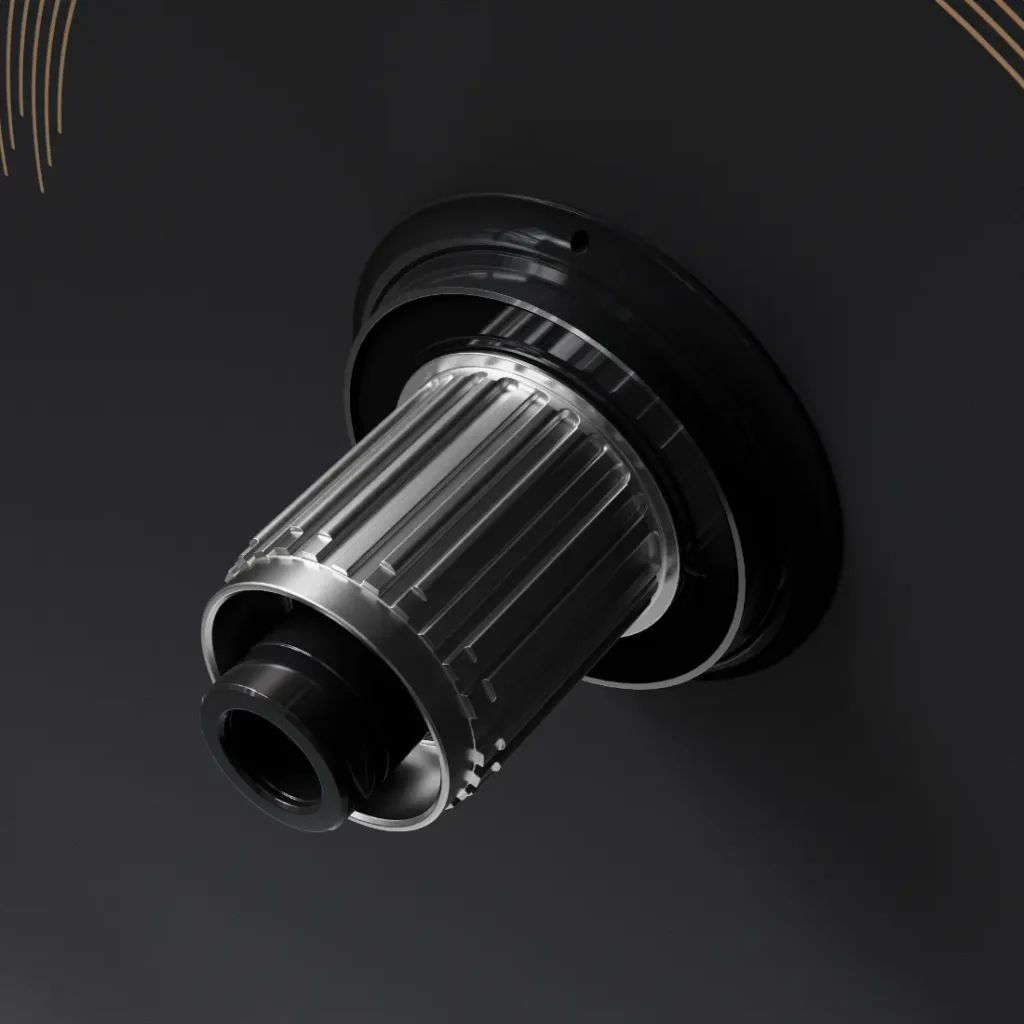 Primer plano de un componente metálico del buje de una bicicleta montado sobre una superficie negra, con ranuras y salientes para su fijación; compatible con las ruedas WH-R9370 Ruedas Shimano Dura-Ace y diseñado para admitir radios de carbono de última generación.
