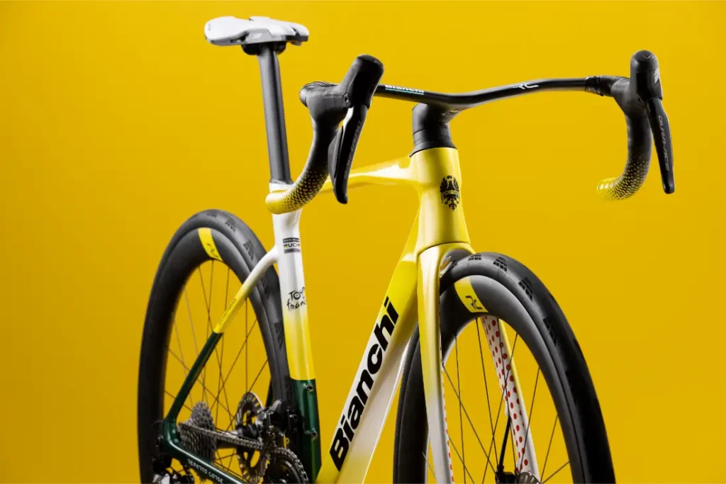 Primer plano de una bicicleta de carretera Bianchi amarilla y blanca sobre un fondo amarillo liso, en el que se aprecian el manillar, el sillín y la rueda trasera.