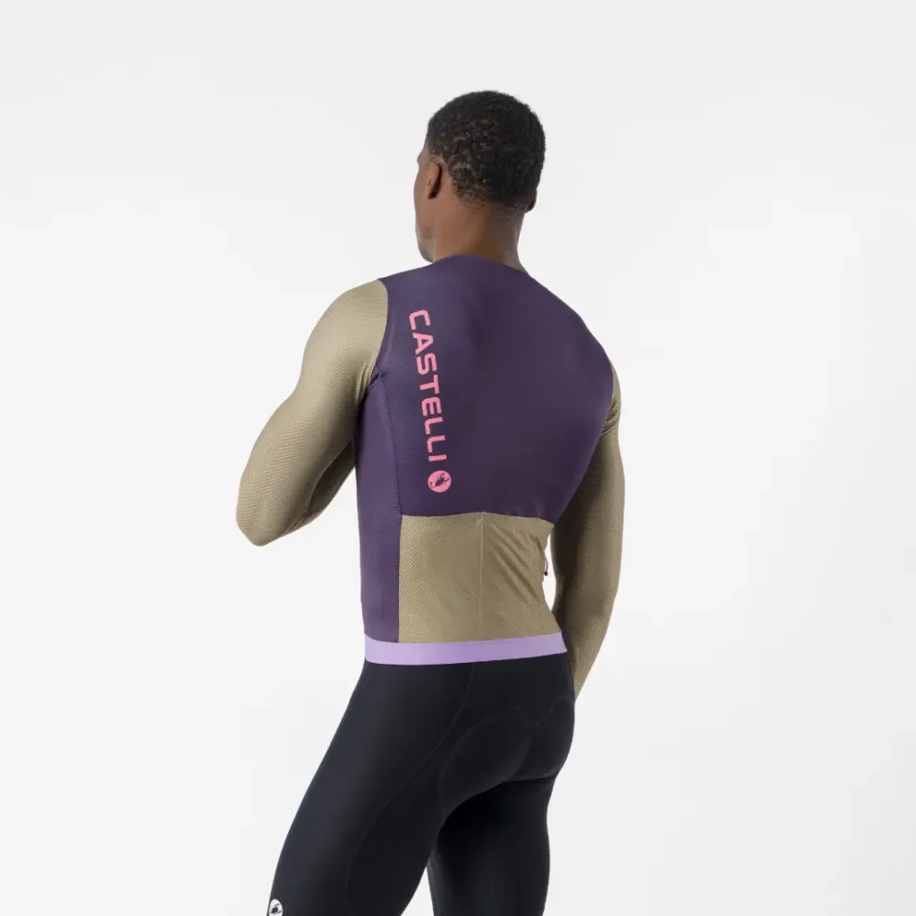 Un hombre de espaldas, que lleva un maillot Corretto LS en colores morado y beige con la inscripción «CASTELLI» en vertical en la espalda, en el que destaca el elegante diseño de este maillot de manga larga Castelli Transition, combinado con unos culotes de ciclismo negros, sobre un fondo blanco liso.