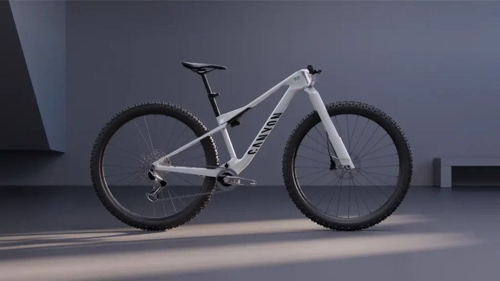 Una bicicleta de montaña rígida de color blanco, con neumáticos negros y la marca «Canyon» en el cuadro, expuesta en un interior sobre un fondo neutro, encarna la revolución industrial gracias a su diseño avanzado y a características como las ruedas de 32, que garantizan un rendimiento óptimo en cualquier terreno.