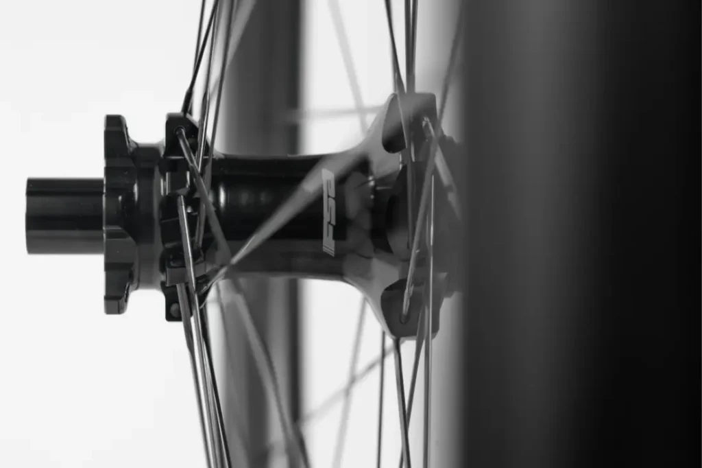 Primer plano del buje de una rueda de bicicleta con los radios que se extienden hacia fuera, fotografiado en blanco y negro sobre un fondo claro.