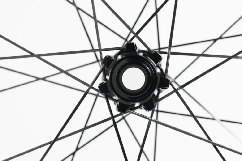 Primer plano del buje y los radios de una rueda de bicicleta, vistos desde el centro, sobre un fondo blanco.