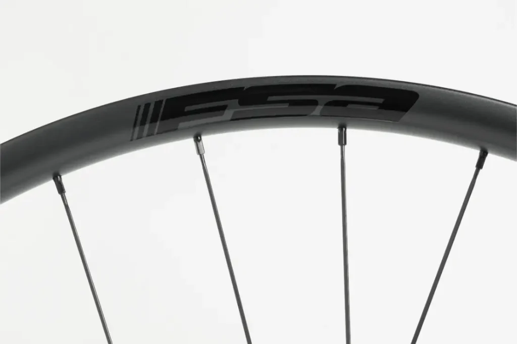 Primer plano de una llanta de bicicleta negra con radios plateados y el logotipo «FSA» impreso en negro en la llanta.