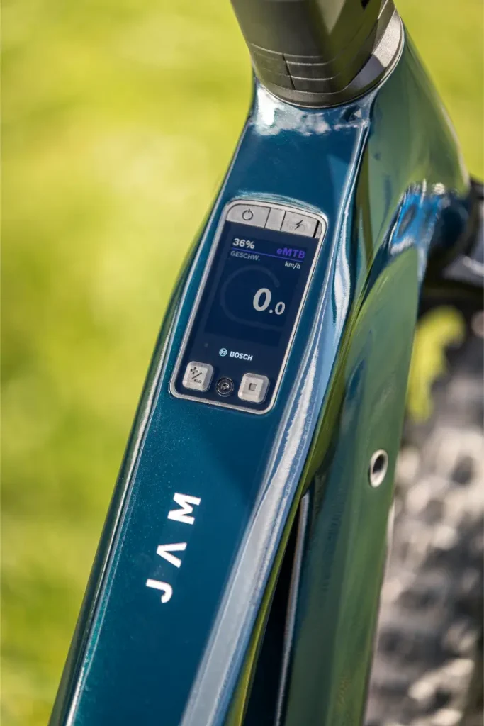 Primer plano de la pantalla situada en el tubo superior de una bicicleta eléctrica de montaña Gama FOCUS 2027, en la que se muestra un nivel de batería del 36 %, una velocidad de 0,0 y el modo eMTB, con la palabra «JAM» impresa en el cuadro.