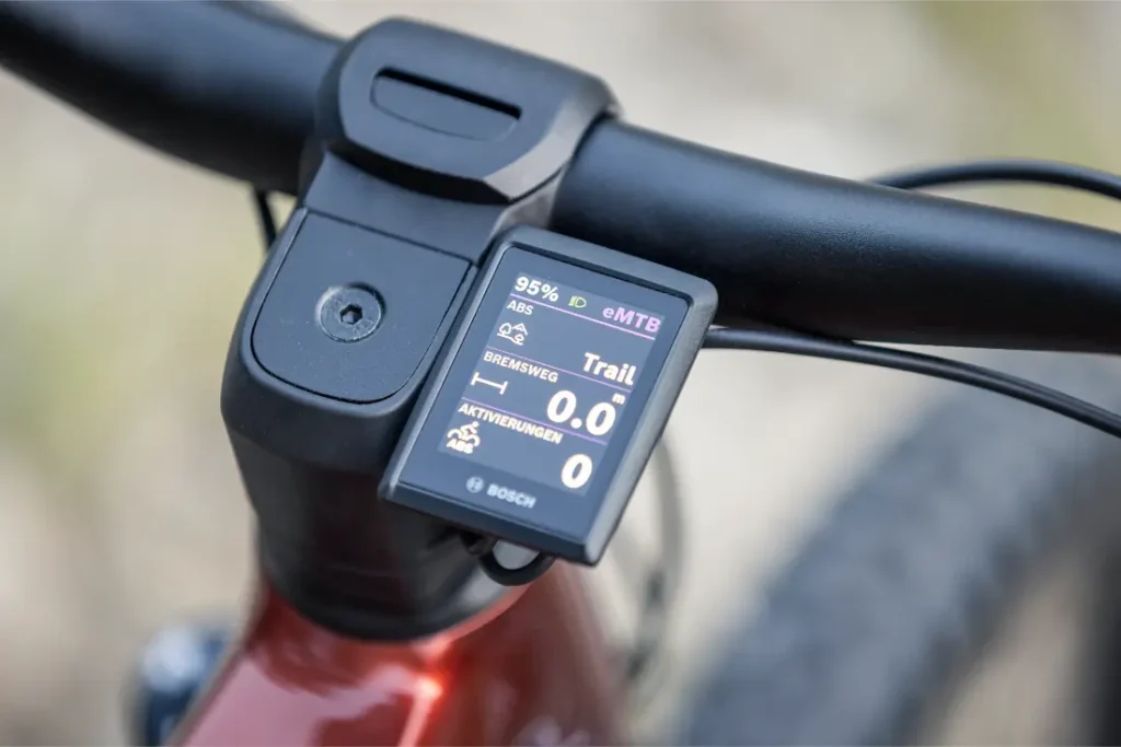 Primer plano del manillar de una bicicleta eléctrica de montaña Gama FOCUS 2027 con una pantalla Bosch que muestra el nivel de batería, la velocidad, el modo y otra información de conducción: perfecta para tu próxima aventura JAM o SAM.