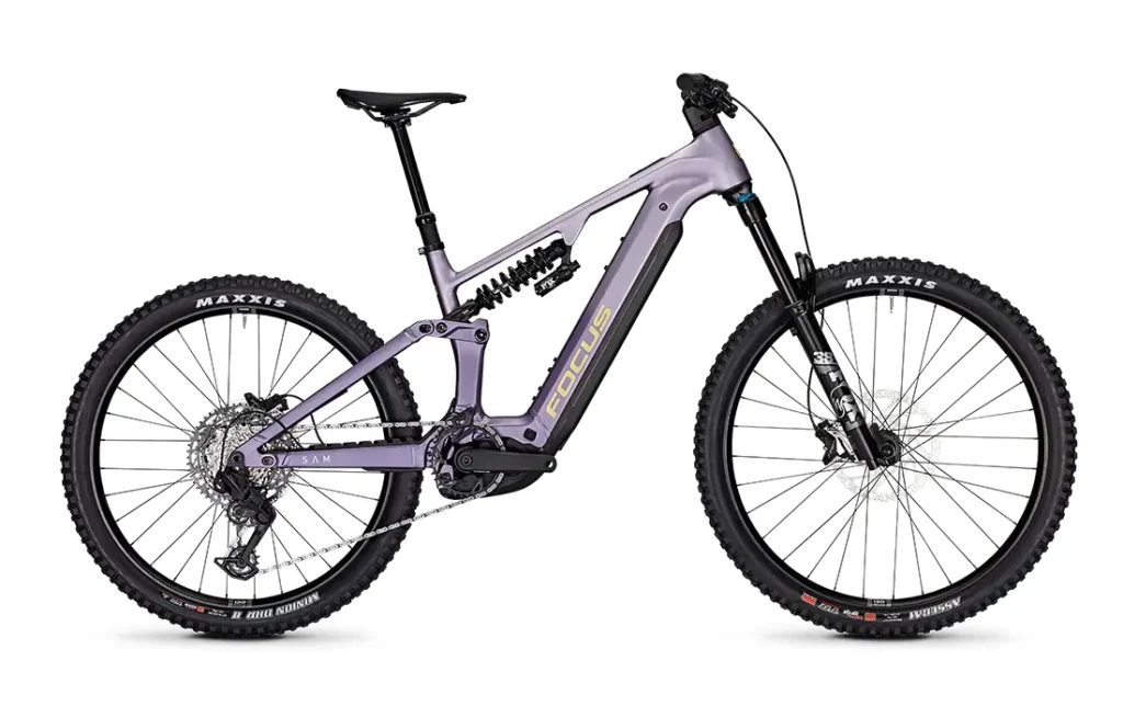 Una bicicleta de montaña eléctrica (e-MTB) de 2027 con suspensión total, con un llamativo cuadro morado, frenos de disco, neumáticos Maxxis de gran anchura y una batería central, vista de perfil.