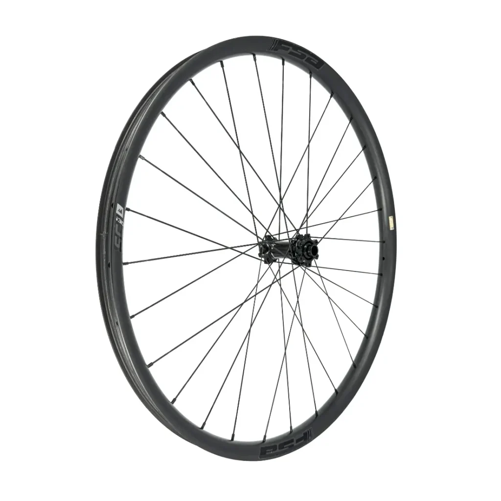 Una rueda de bicicleta negra con radios finos y un buje visible, fotografiada sobre un fondo blanco liso.