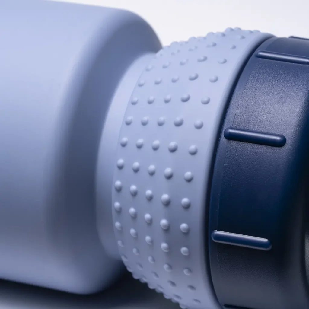Primer plano de una botella de agua o termo azul claro con textura y tapón azul oscuro, en el que se aprecian la zona de agarre y parte de la tapa. Con el diseño «Fabric Gripper V2», este bidón antimicrobiano ofrece protección permanente para el uso diario.