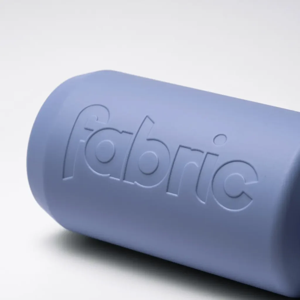 El bidón antimicrobiano Fabric Gripper V2, un objeto cilíndrico de color morado claro con la palabra «fabric» grabada en relieve sobre un fondo blanco, ofrece protección permanente para tus necesidades de hidratación.
