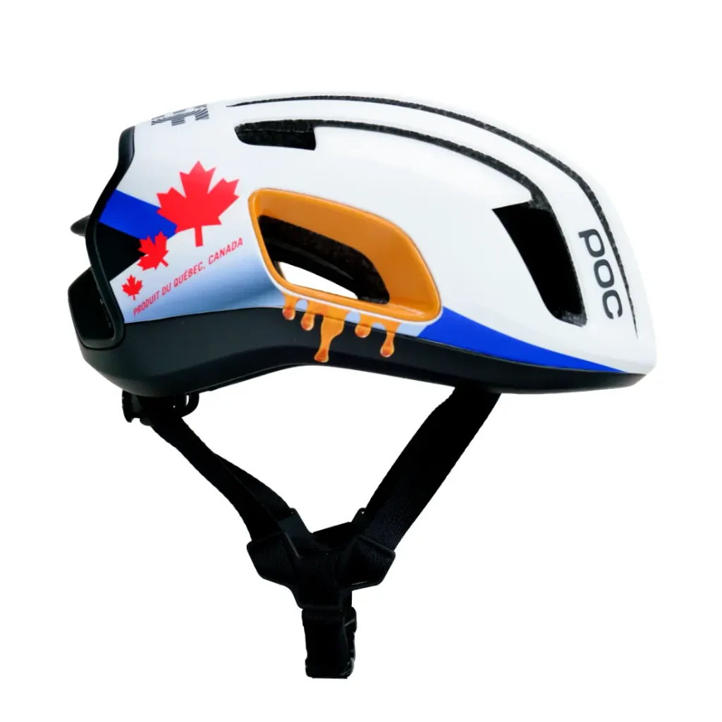 Casco de bicicleta blanco con correas negras, decorado con una hoja de arce roja, la inscripción «Proudly of Quebec, Canada» y detalles gráficos de color naranja. Se aprecia el nombre de la marca «POC».