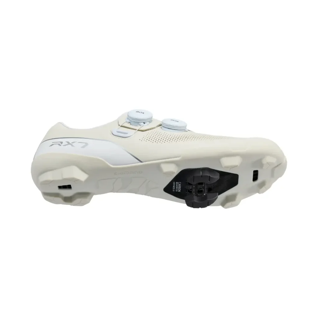 Unas zapatillas de ciclismo blancas Shimano RX710 con doble cierre de dial y una cala integrada en la suela, que incorporan tecnología de competición ideal para salidas de gravel, mostradas sobre un fondo blanco liso.