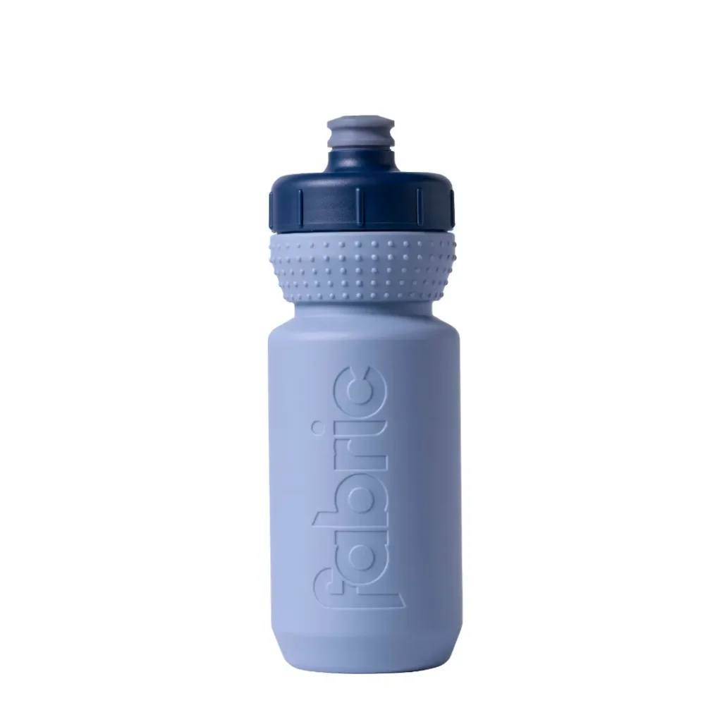Una botella de agua de plástico «Fabric Gripper V2» de color azul claro, con un tapón azul marino texturizado y la palabra «fabric» grabada en relieve en el lateral; esta botella antimicrobiana está diseñada para ofrecer tanto higiene como comodidad.