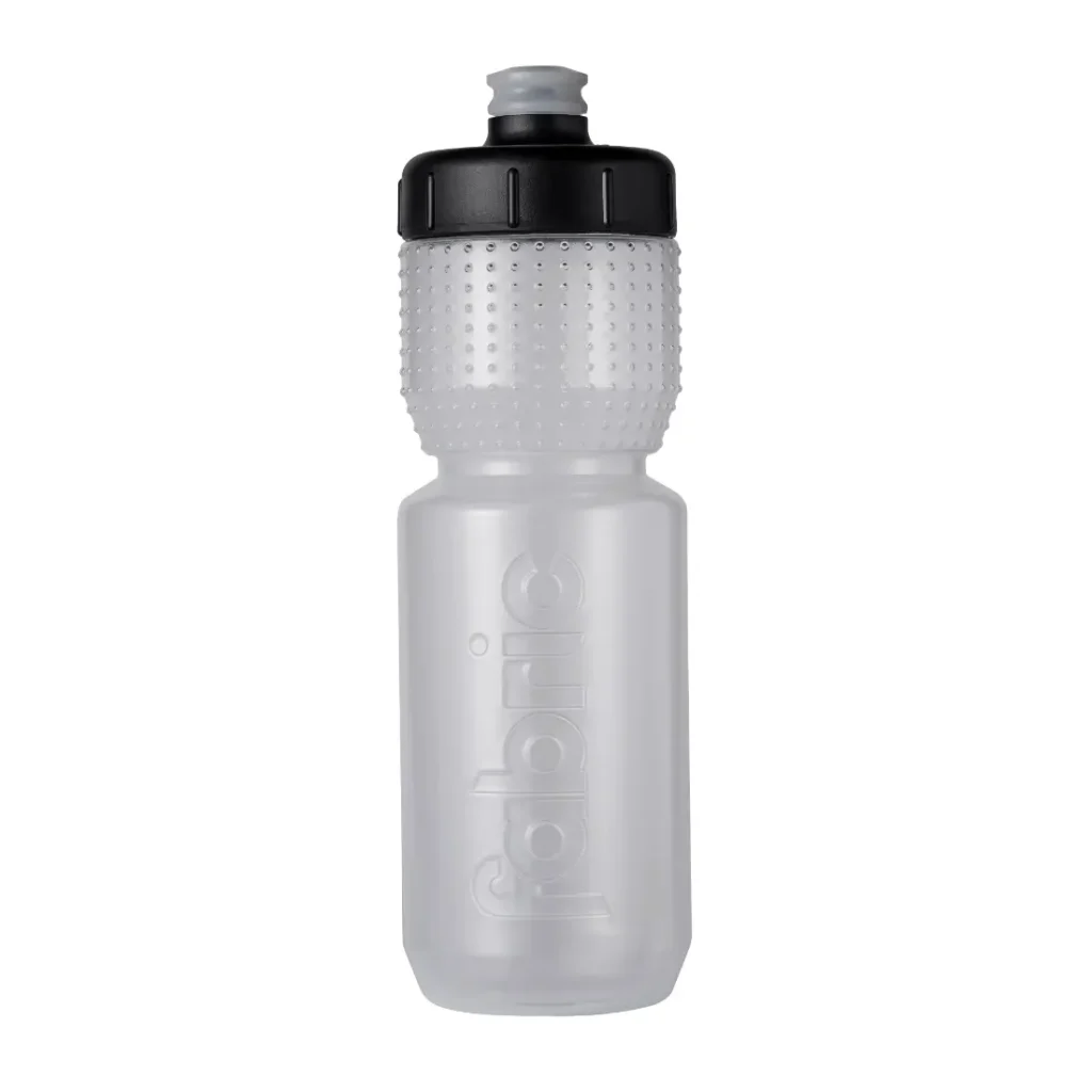 Botella de agua de plástico transparente con tapón negro texturizado, en cuyo cuerpo aparece grabada en relieve la palabra «fabric» en vertical. Esta botella Fabric Gripper V2 garantiza una hidratación fiable y cuenta con protección antimicrobiana para una mayor higiene.
