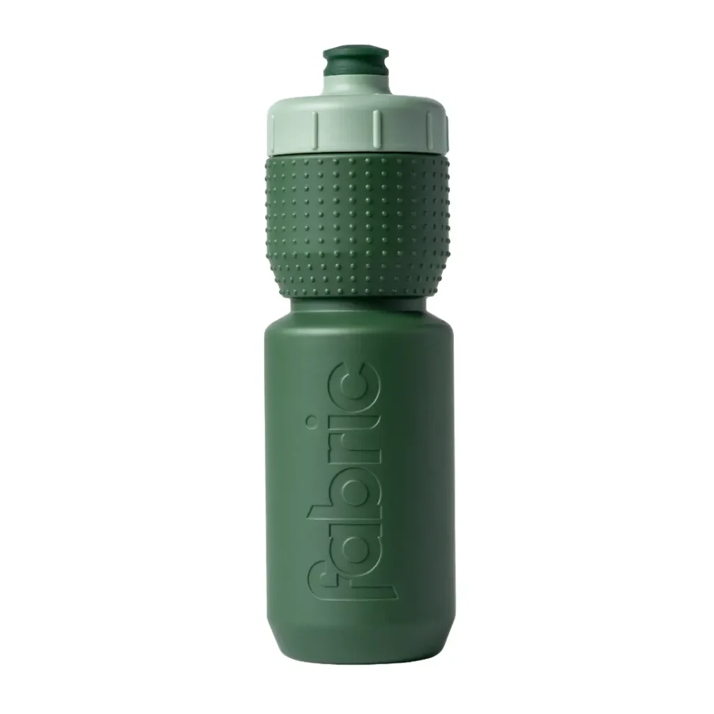Botella de agua de plástico reutilizable de color verde con agarre texturizado y tapón de rosca. La palabra «fabric» aparece grabada en relieve verticalmente en el lateral de la botella, lo que destaca su diseño «Fabric Gripper V2» para un mejor agarre. Esta botella antimicrobiana también cuenta con protección permanente para ayudarte a mantener tu hidratación limpia y fresca.