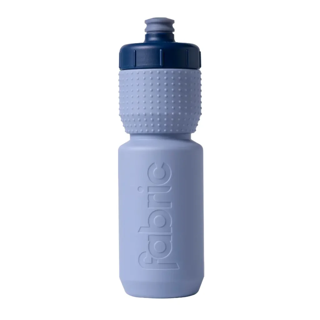 Botella de agua de plástico azul claro con agarre texturizado y tapón azul oscuro, en cuyo lateral aparece la palabra «fabric» grabada en relieve en vertical. Este bidón antimicrobiano Fabric Gripper V2 ofrece protección permanente para tus necesidades de hidratación.