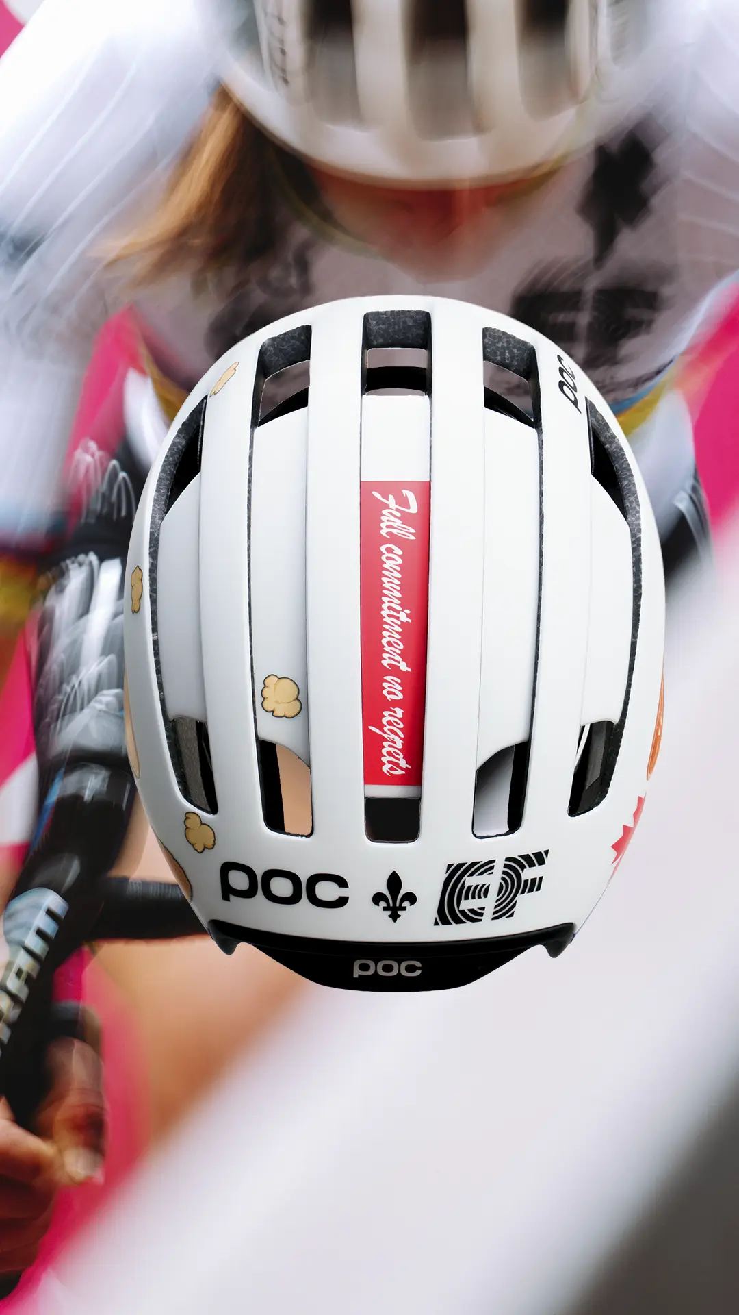 Ciclista con un casco POC blanco con varias pegatinas, entre ellas una roja en la que se lee «Total compromiso, sin resultados», montado en bicicleta.