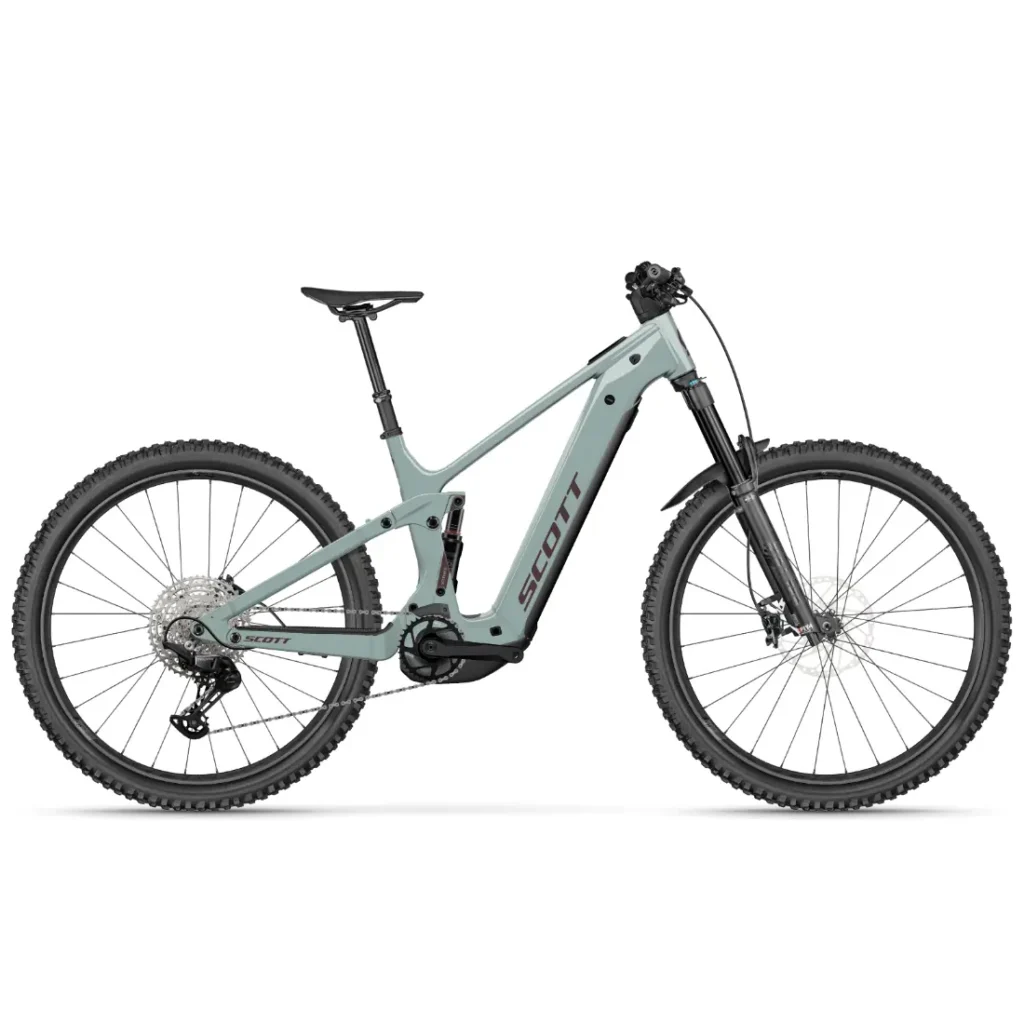 Se muestra, de perfil y sobre un fondo blanco, una bicicleta de montaña eléctrica SCOTT Strike 2027 de color gris claro, con suspensión delantera, neumáticos anchos y un tubo superior inclinado. Equipada con un motor Bosch CX para mayor comodidad, esta versátil bicicleta eléctrica está diseñada tanto para recorridos suaves como para terrenos accidentados.
