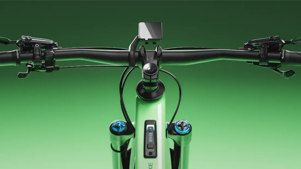Primer plano del manillar de una bicicleta SCOTT Strike 2027 con pantalla digital y mandos, equipada con el potente motor Bosch CX para una mayor comodidad, sobre un fondo verde con degradado.