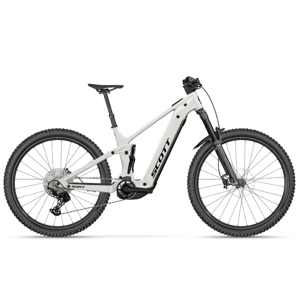 En una vista lateral sobre un fondo liso se muestra una bicicleta de montaña eléctrica SCOTT Strike 2027 de color blanco, con suspensión total, frenos de disco y neumáticos con tacos, equipada con un motor Bosch CX para mayor comodidad.