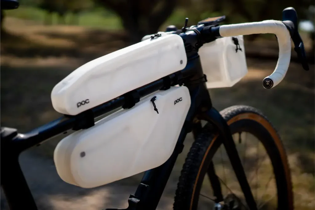 Una bicicleta negra cuenta con tres bolsas de almacenamiento blancas de la marca POC fijadas al cuadro y al manillar, que ofrecen un mejor tacto y mayor comodidad gracias a la cinta de manillar Silca Nastro Cuscino.
