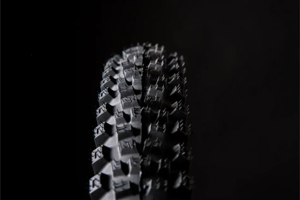 Primer plano de un neumático negro Pirelli Scorpion para bicicleta de montaña con dibujo de tacos, fotografiado sobre un fondo oscuro. Perfectos para afrontar senderos que desafían la gravedad, estos neumáticos de MTB están diseñados para ofrecer el máximo agarre y control.