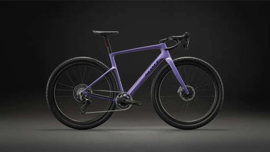 Una bicicleta de gravel de color morado, con manillar de carretera y frenos de disco, se ve sobre un fondo oscuro, vista de perfil, lo que refleja la versatilidad de una bicicleta polivalente como la SCOTT Addict Gravel 2027.