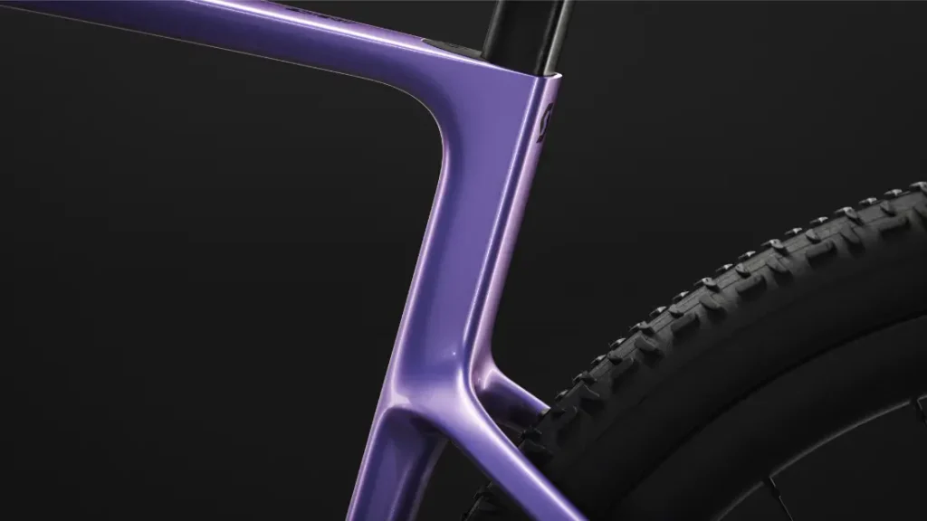 Primer plano del cuadro y la rueda trasera de una bicicleta SCOTT Addict Gravel 2027 de color morado sobre un fondo negro, en el que se destacan los contornos suaves, la geometría cómoda y el moderno diseño gravel de la bicicleta.