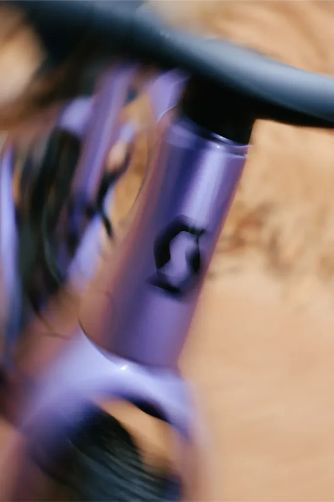Primer plano de un cuadro de bicicleta SCOTT Addict Gravel 2027, de color morado, polivalente y cómodo, con el logotipo en negro, el manillar y un fondo difuminado.