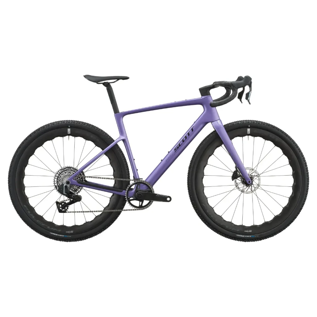 Se muestra de perfil, sobre un fondo blanco, una bicicleta SCOTT Addict Gravel 2027 de color morado, con manillar de carretera, frenos de disco, neumáticos anchos y un elegante cuadro de carbono. Esta bicicleta de gravel polivalente combina un diseño moderno con un rendimiento versátil para todas tus aventuras.