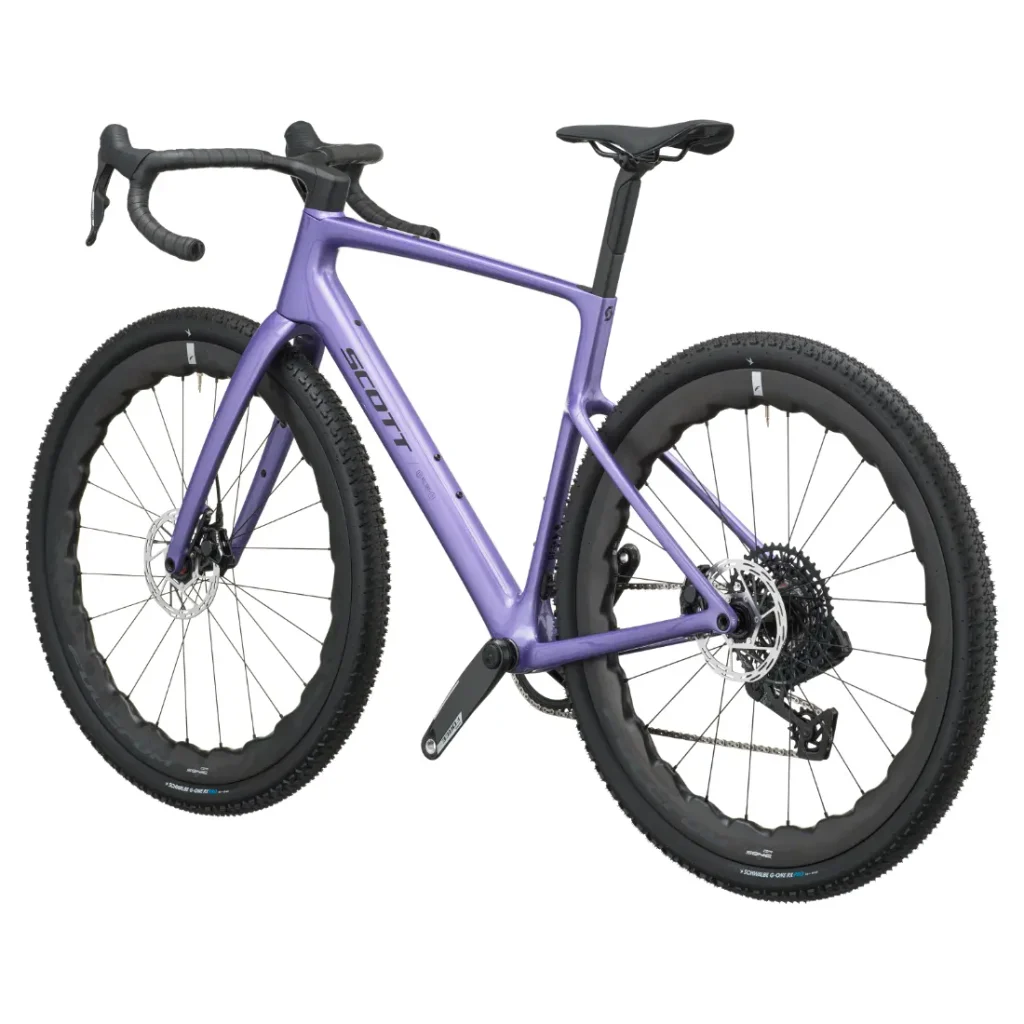 Bicicleta SCOTT Addict Gravel 2027 de color morado, con manillar de carretera, neumáticos anchos con tacos, frenos de disco y cuadro de carbono, vista de perfil sobre un fondo blanco: una opción versátil y cómoda para los ciclistas más exigentes.