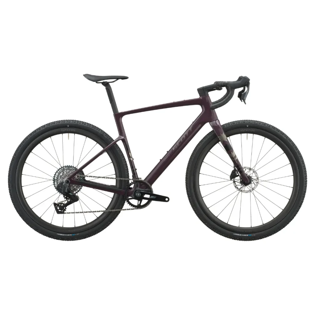 Se muestra de perfil, sobre un fondo blanco, una bicicleta gravel SCOTT Addict Gravel 2027 de color morado oscuro, con manillar de carretera, neumáticos anchos y cuadro de carbono, que combina un diseño elegante con una posición de conducción cómoda.